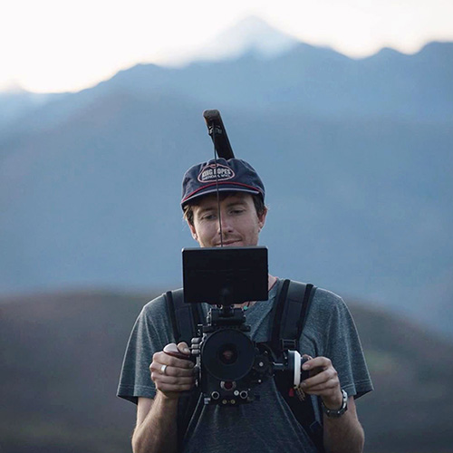 man holds camera against his chest