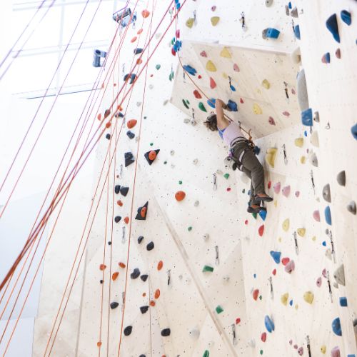 a person lead climbing up an indoor climbing wall