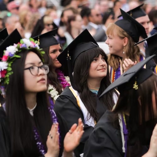 students in graduation regalia are shown seated at the 2025 commencement.