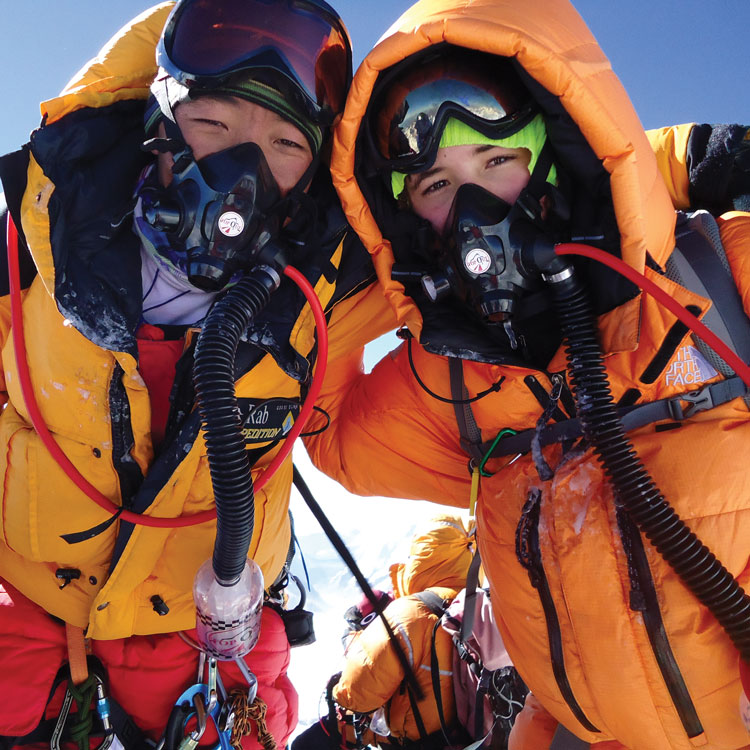 Two hikers on snowy mountain with masks
