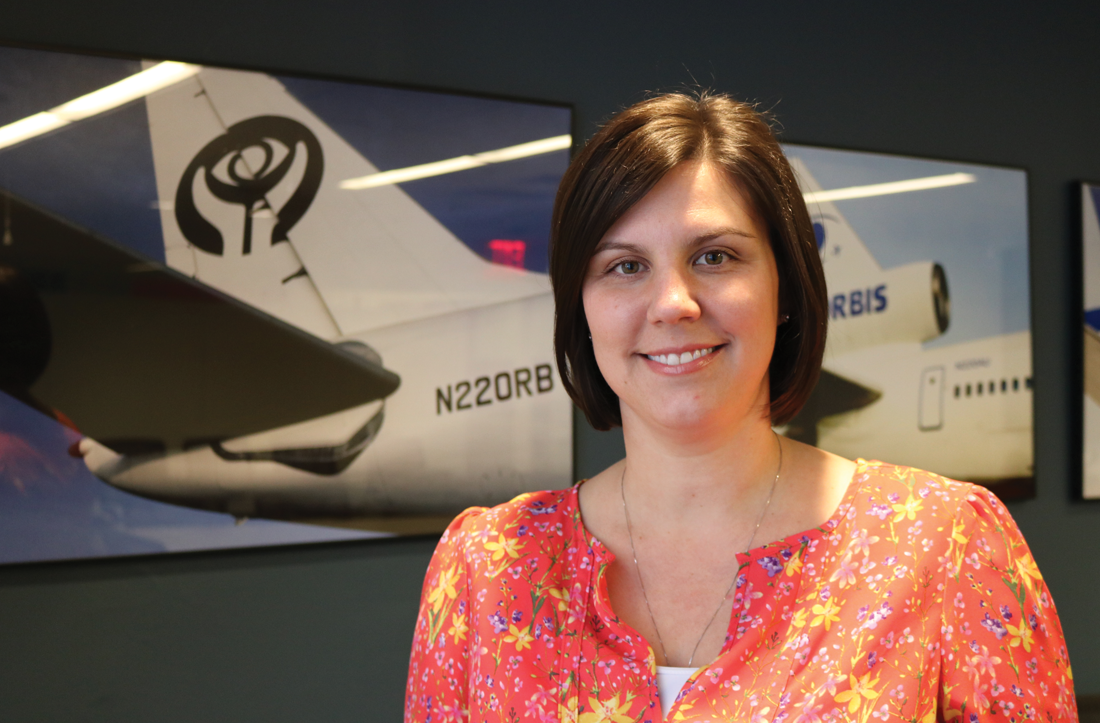 Westminster alum Aleesa (Kurtz) Radoncic poses in front of pictures of airplanes.