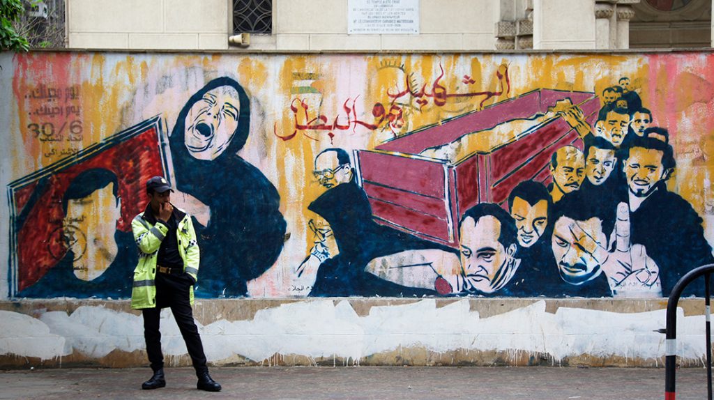 An Egyptian police officer keeps watch over a church in downtown Cairo in front of a mural that reads, “the martyr is the hero.” 