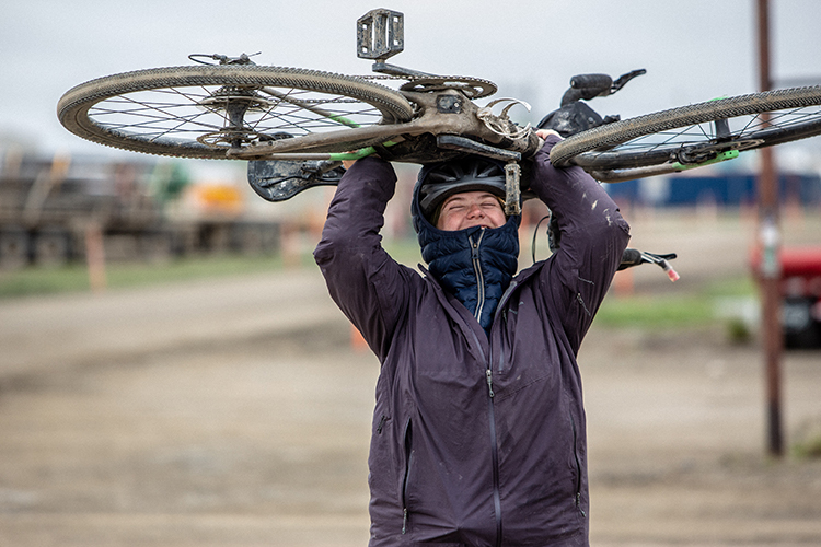 Kailey Kornhauser holding a bike above their head