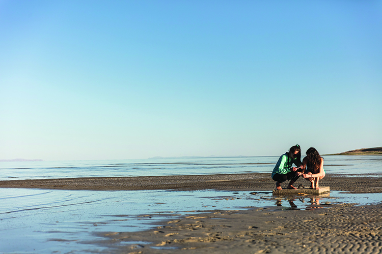 two female students sitting down on shore of the Great Sale Lake 