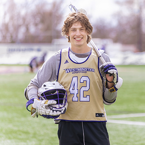 male lacrosse player on the field holding his gear