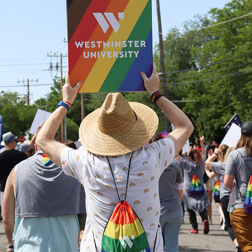 parade goer holding up rainbow Westminster University sign during Pride Parade