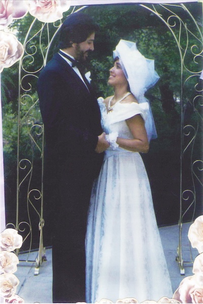 woman in a bridal dress and man in a suit standing under an arch